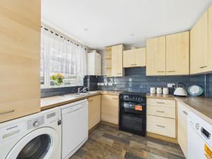 a kitchen with wooden cabinets and a washer and dryer at The Costwold Haven in Shurdington