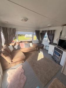 a living room with a couch and a tv at Hoopers Hideaway Caravan Rental SetonSands 2 in Port Seton