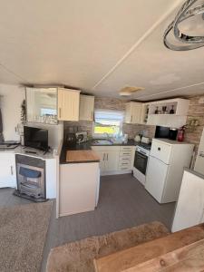 a small kitchen with white cabinets and appliances at Hoopers Hideaway Caravan Rental SetonSands 2 in Port Seton +4 photos