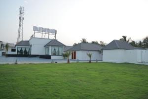 a row of white houses with a green lawn at Dee Cottage kanyakumari in Kanyakumari