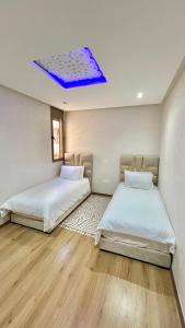 two beds in a room with a blue ceiling at A2 Luxe Moderne et Confort, 7 min du Stade Moulay Abdellah in Temara