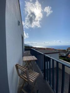 a wooden chair on a balcony with a view of the ocean at Refugio do Falcão in Ponta Garça