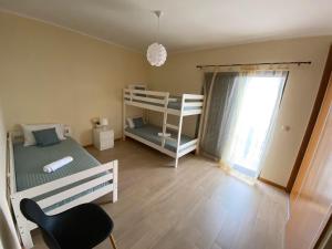 a bedroom with two bunk beds and a chair at Refugio do Falcão in Ponta Garça
