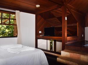 a bedroom with a bed and a window with a tv at Pousada do Encanto in Visconde De Maua