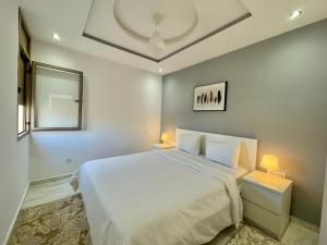 a bedroom with a large white bed and two lamps at A2 Luxe Moderne et Confort, 7 min du Stade Moulay Abdellah in Temara