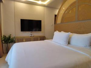 a bedroom with a white bed with a flat screen tv at Dahican Beach Resort and Spa in Sampong