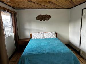 a bedroom with a bed with a blue comforter and a window at hotel Rarámuri in Creel
