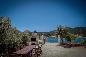 une table de pique-nique et des bancs à côté d'une masse d'eau dans l'établissement Villa Albatros, à Vinišće