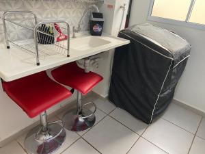 a bathroom with a sink and a red stool next to a trash can at Apto térreo, próx ao Centro, Sesi, Bioethicus, fácil acesso à Unesp in Botucatu
