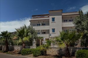 a large building with palm trees in front of it at Villa Albatros in Vinišće