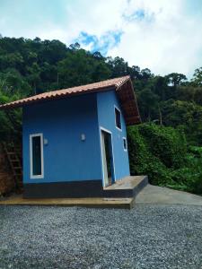 a blue small house with a hill in the background at Chalé Studio Haven, microcasa com Mezanino e banheira in Lumiar