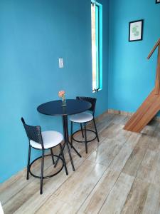 a table and chairs in a room with a blue wall at Chalé Studio Haven, microcasa com Mezanino e banheira in Lumiar