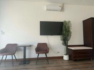 a room with two chairs and a table and a tv at Roomz at Rawai in Ban Saiyuan (1)