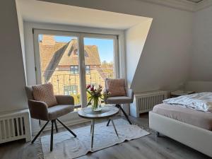 a bedroom with two chairs and a table and a window at Ferienwohnung-Weidenstieg-OG in Wenningstedt