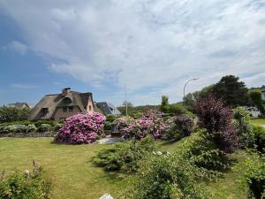 a house with flowers in front of a yard at Ferienwohnung-Weidenstieg-OG in Wenningstedt