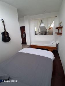 a bedroom with a bed and a guitar on the wall at Pescadito in Puerto Ayora