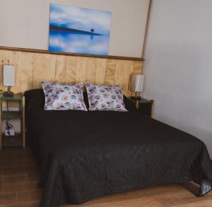 a bedroom with a black bed with two pillows at Aware in Capilla del Monte