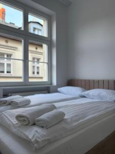 a white bed with towels on it with a window at Armonia Old Town in Poznań