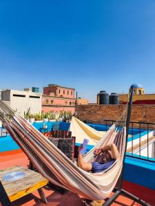 a woman laying in a hammock on a roof at Sukha Hostel San Luis in San Luis Potosí