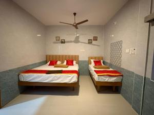 a bedroom with two beds and a ceiling fan at Shanmikha Residency - Attur - Near Highways in Āttūr