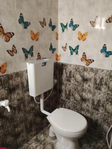 a bathroom with a toilet and butterflies on the wall at Shanmikha Residency - Attur - Near Highways in Āttūr