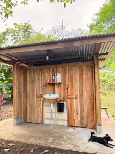 a dog laying in front of a wooden shed at Camping Los Búfalos in Guácimo
