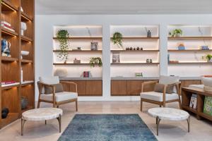 a room with chairs and shelves with plants at Sandblu Santorini, LXR Hotels & Resorts in Kamari