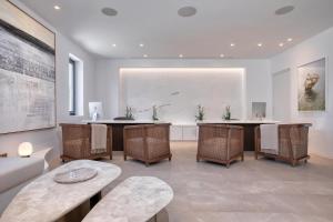 a living room with tables and chairs and a painting at Sandblu Santorini, LXR Hotels & Resorts in Kamari