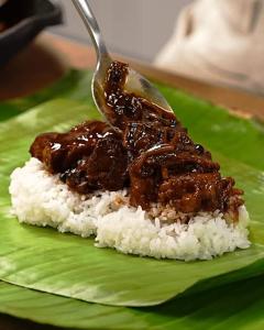 a piece of meat on top of rice on a green plate at HALASE HOMESTAY mudigere in Mudigere