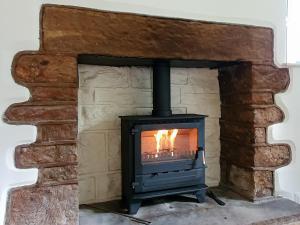 a wood stove in a stone fireplace at Colby Hall Cottage in Colby