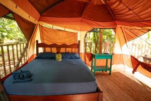 a bedroom in a tent with a bed and a table at Dolphin Quest Jungle Lodge in Piedras Blancas
