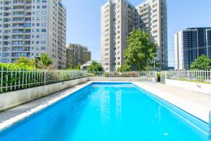 a blue swimming pool with tall buildings in the background at Alta vista Concepción in Concepción