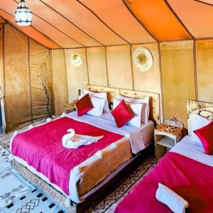 a bedroom with two beds in a tent at Merzouga Traditional Camp in Merzouga