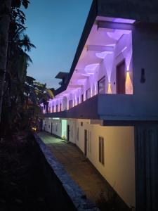 a row of white buildings with purple lights on them at Poozhikuth Homestay in Sultan Bathery