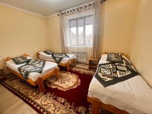 a room with two beds and a window at Tündük Guest House, Karakol in Karakol