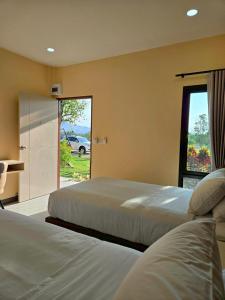 two beds in a hotel room with a window at The Y Habitat in Kanchanaburi City +17 photos