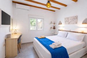 a white bedroom with a bed and a desk at Eressian Lodgings - Skala Eressos in Skala Eresou