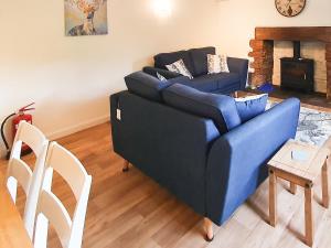 a blue couch in a living room with a fireplace at Colby Hall Cottage in Colby