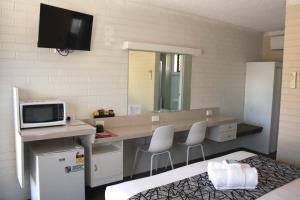 a bathroom with a counter with a tv and chairs at Coastal Bay Motel in Coffs Harbour