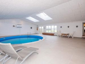 a swimming pool in a room with chairs and a table at 4 star holiday home in Allingåbro in Allingåbro