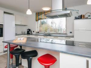 a kitchen with a large counter with red stools at 4 star holiday home in Allingåbro in Allingåbro
