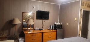 a hotel room with a dresser with a tv on the wall at Neepawa Motel in Neepawa