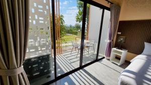 a room with a balcony with a bed and a table at The Y Habitat in Kanchanaburi City