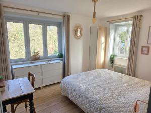 a bedroom with a bed and a table and windows at Le cottage de Cassandre in Sebourg