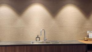 a kitchen counter with a sink and shadows on the wall at Myeongwolga Poolvilla in Busan