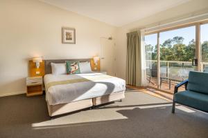 a bedroom with a bed and a chair and a window at Eagle Heights Mountain Resort in Eagle Heights