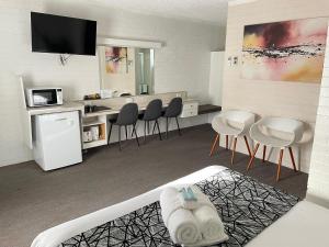 a living room with chairs and a kitchen at Coastal Bay Motel in Coffs Harbour