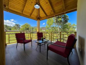 a screened porch with chairs and a table and a view at Villa Campo Verde in Jarabacoa