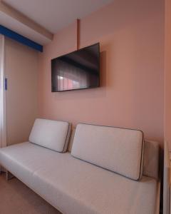 a couch with a flat screen tv on a wall at THE BASEMENT HOTEL OsakaHonmachi in Osaka