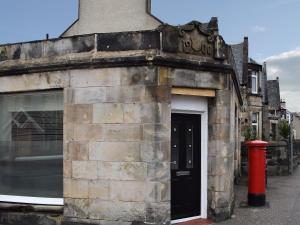 an old stone building with a black door and a red fire hydrant at Bramble Cottage in Leven
